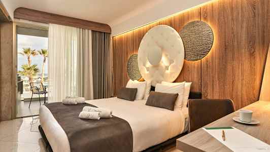 Hotellrum med en stor säng, dekorerad vägg och öppen balkong med utsikt. (AI-genererad text)