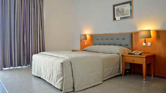 Hotellrum med en säng och två sänglampor. (AI-genererad text)