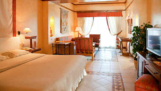 Interiör av ett hotellrum med en dubbelsäng, sittgrupp och inredningsdetaljer. (AI-genererad text)