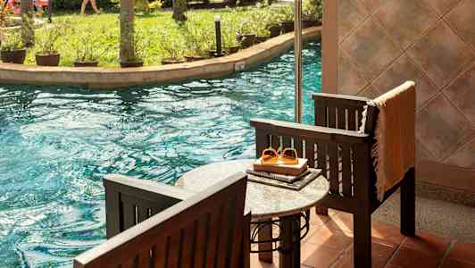 Terrass vid poolen med utsikt mot en trädgård och vattenrutschbana. (AI-genererad text)