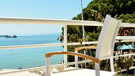 En vit stol står på en balkong med utsikt över havet. (AI-genererad text)