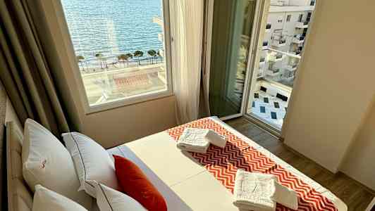 Ett hotellrum med en säng, fönster med utsikt över havet och handdukar på sängen. (AI-genererad text)