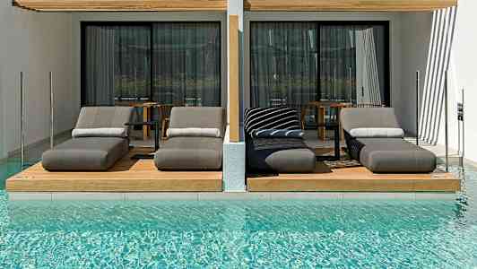 Lyxiga solsängar vid en pool framför moderna hotellrum. (AI-genererad text)