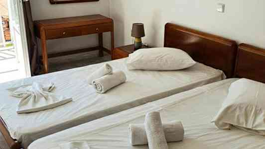 Två enkelsängar med vita lakan och handdukar placerade ovanpå, samt ett bord och en spegel i rummet. (AI-genererad text)