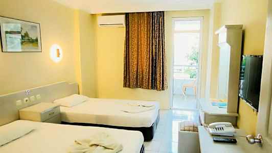 Hotellrum med två enkelsängar, skrivbord och TV. (AI-genererad text)