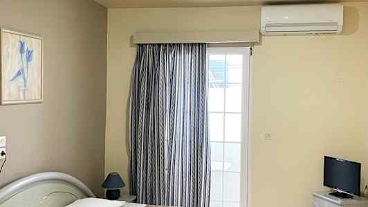 Hotellrum med två enkelsängar, en TV och ett fönster med gardiner. (AI-genererad text)