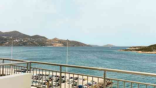 Utsikt från en balkong mot havet med berg i bakgrunden. (AI-genererad text)