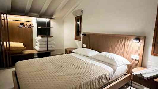 Ett varmt inrett sovrum med en stor säng, sängbord och ett klädställ. (AI-genererad text)