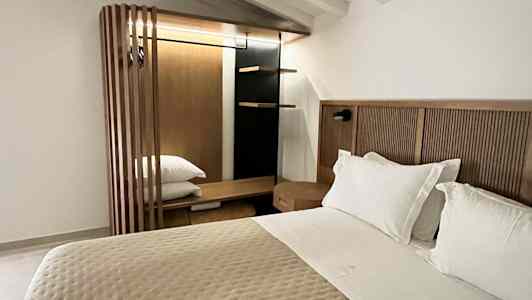 Ett sovrum med en dubbelsäng, vit takpanel och en garderob i trä. (AI-genererad text)