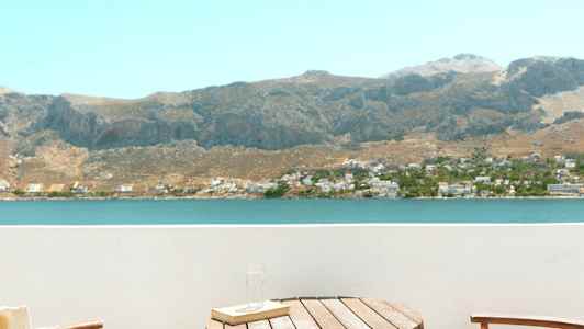 Två stolar och ett bord på en balkong med utsikt över en sjö och berg. (AI-genererad text)