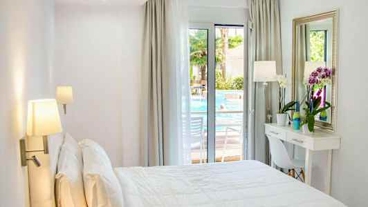 Ljus hotellrum med en bäddad dubbelbädd, ett skrivbord och fönster mot poolområdet. (AI-genererad text)