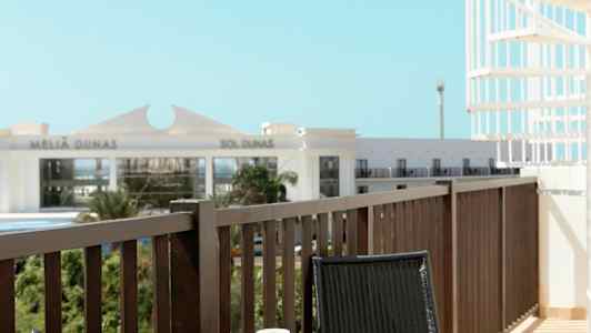 En balkong med ett bord och två stolar. På bordet finns en kaffekopp och en öppnad bok. (AI-genererad text)