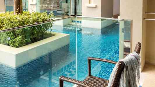 En balkong med utsikt över en pool och närliggande byggnader. (AI-genererad text)