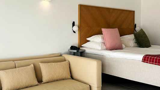 Ett hotellrum med säng och soffa samt ett bord. (AI-genererad text)