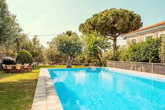 En utomhuspool med gröna träd och en byggnad i bakgrunden. (AI-genererad text)