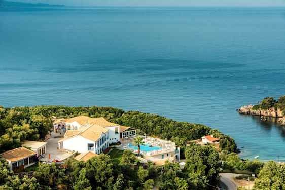 Hotellbyggnad med pool och omgivande grönska vid havet. (AI-genererad text)