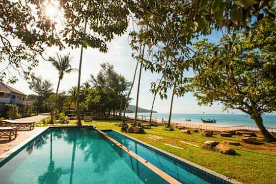 Bild av en swimmingpool med grönt friluftsområde och utsikt över havet i bakgrunden. (AI-genererad text)