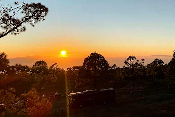 Bild av en solnedgång över en skog med ett fordon i förgrunden. (AI-genererad text)