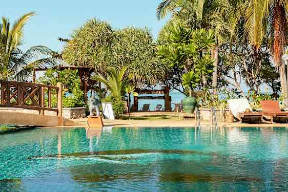 En pool med solstolar intill, och bakom finns träd och en skylt med texten 'Lanta Villa'. (AI-genererad text)