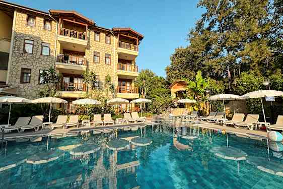 Bild av hotellfasad med pool och solstolar framför. (AI-genererad text)