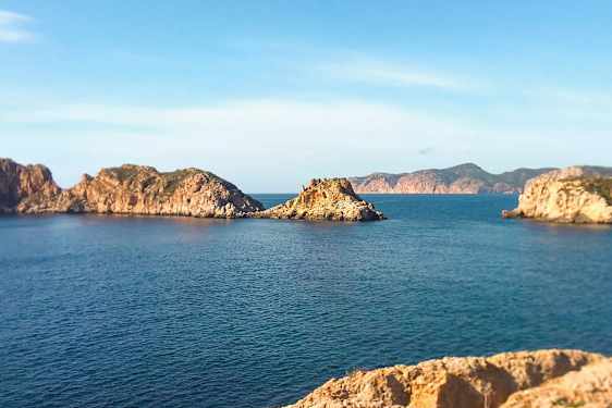 Kustlandskap med klippiga öar i havet under en klar blå himmel. (AI-genererad text)