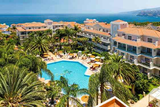 Hotell med poolområde och omgivande grönska vid kusten. (AI-genererad text)