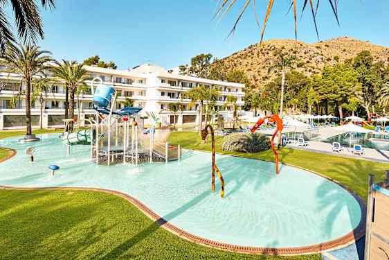 Barnpool med vattenlek och hotellbyggnad i bakgrunden. (AI-genererad text)