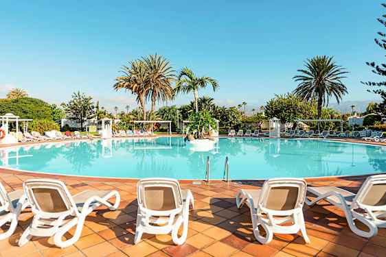 En stor pool omgiven av solstolar och palmer. (AI-genererad text)