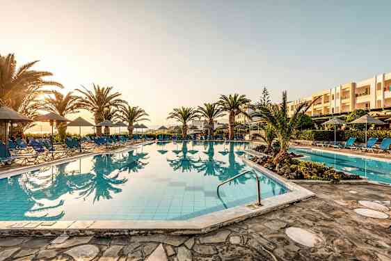 Utomhuspool med solstolar och parasoller vid solnedgång. (AI-genererad text)