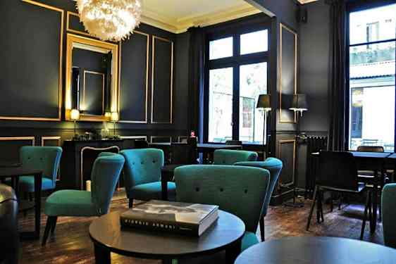 Ett elegant möblerat rum med sittgrupper och blå fåtöljer samt stora fönster. (AI-genererad text)