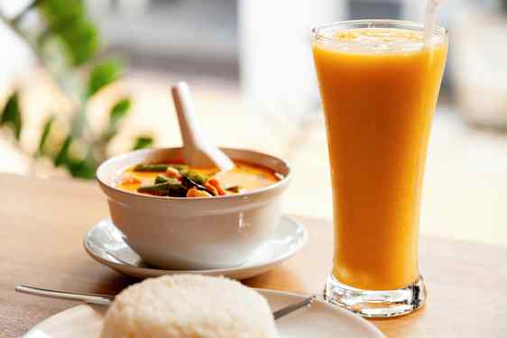 En skål med gul curry, en tallrik med ris och ett glas med gul dryck. (AI-genererad text)