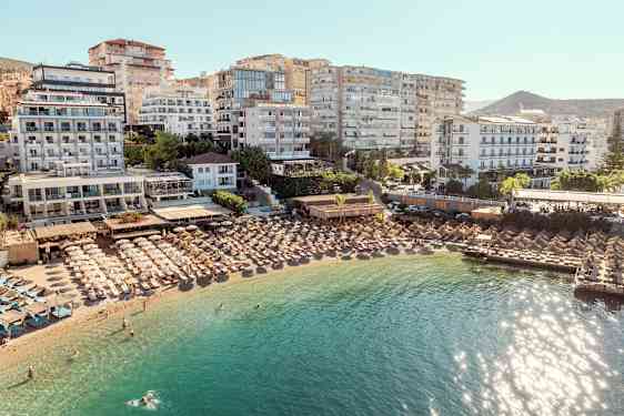 Hotell och parasoller vid en strand med klart vatten. (AI-genererad text)