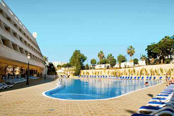 En hotellpool med solstolar runt omkring. (AI-genererad text)