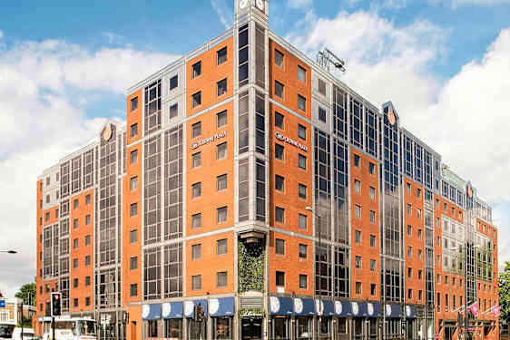 Bild av ett hotell med röd tegel och glasfönster. (AI-genererad text)