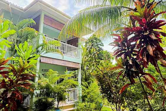 En byggnad med balkonger omgiven av frodig tropisk växtlighet. (AI-genererad text)