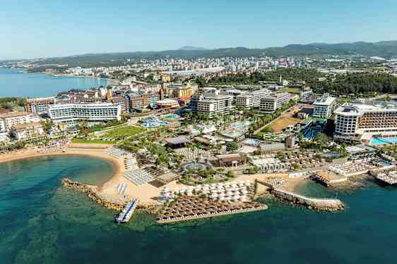 Flygfoto över en semesterort vid kusten med hotell, pooler och stranden. (AI-genererad text)