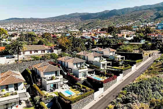 Bild av ett område med moderna hus och små pooler omgivna av grönska och en väg. (AI-genererad text)