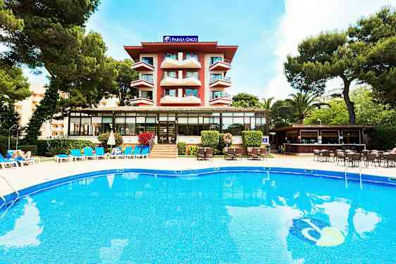 Byggnad med balkonger, pool och solstolar framför, omgiven av grönska. (AI-genererad text)