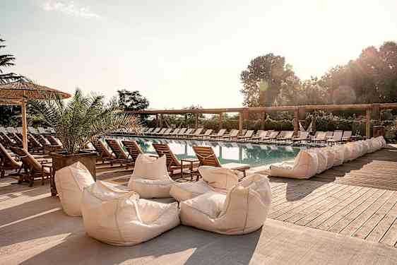 En utomhuspool omgiven av solstolar och sittsäckar. (AI-genererad text)