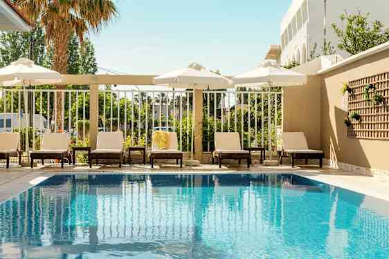 Utomhuspool med solstolar och parasoller vid kanten. (AI-genererad text)