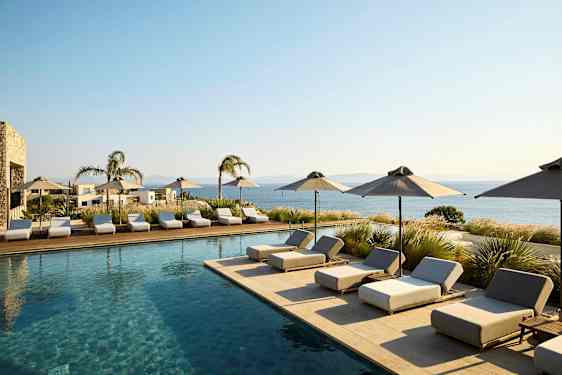 Poolområde med solstolar och parasoller, utsikt mot havet. (AI-genererad text)