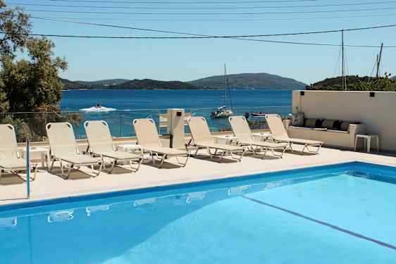 Swimmingpool med solstolar och havsutsikt i bakgrunden. (AI-genererad text)