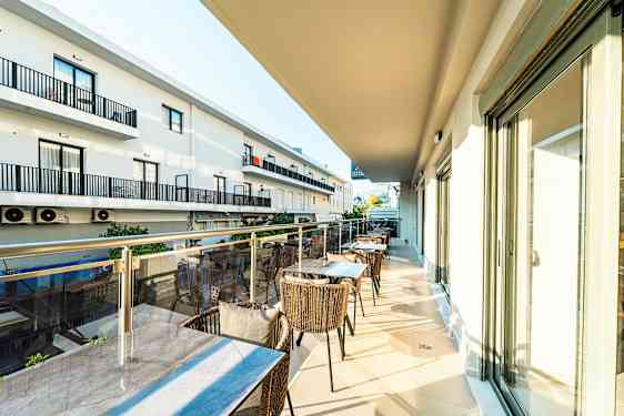 En balkong med bord och stolar, samt vy av grannbyggnader. (AI-genererad text)