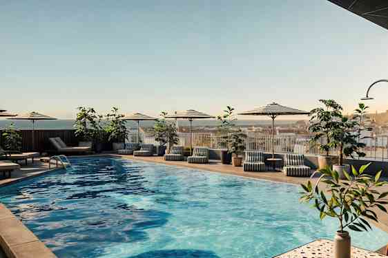 Utomhuspool med parasoller, solstolar och växter runtomkring. (AI-genererad text)