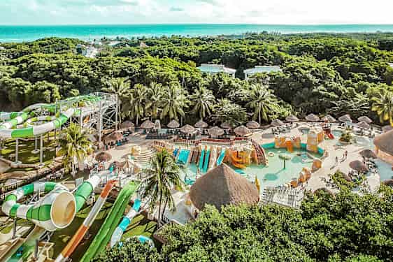 En bild av en vattenpark med vattenrutschbanor, simbassänger och grönska i bakgrunden. (AI-genererad text)