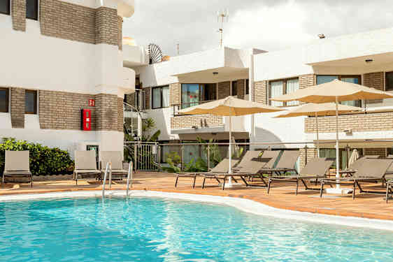 Utomhuspoolområde med solstolar och parasoller vid en byggnad. (AI-genererad text)