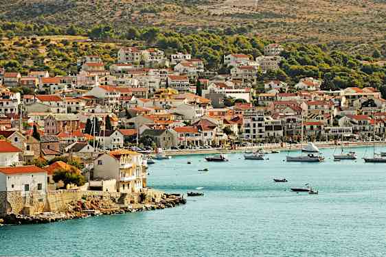 En kuststad med hus nära vattenkanten och båtar i viken. (AI-genererad text)