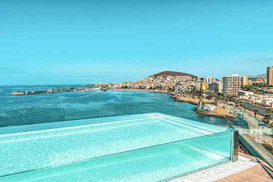 En pool med utsikt över en havsvik och stad nära kusten. (AI-genererad text)