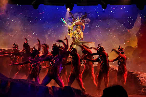 En scenföreställning med dansare iklädda dräkter framför en dekorerad bakgrund. (AI-genererad text)