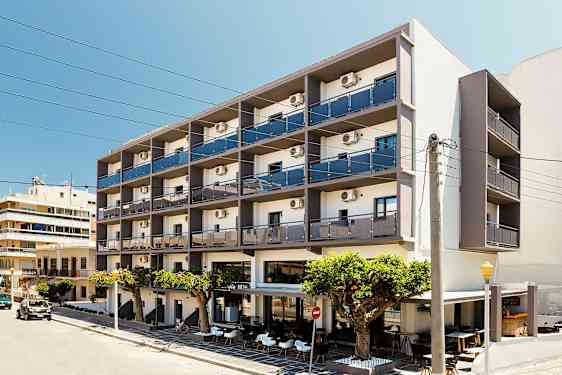 Ett flervåningshotell med balkonger och uteservering framför, beläget vid en gata. (AI-genererad text)